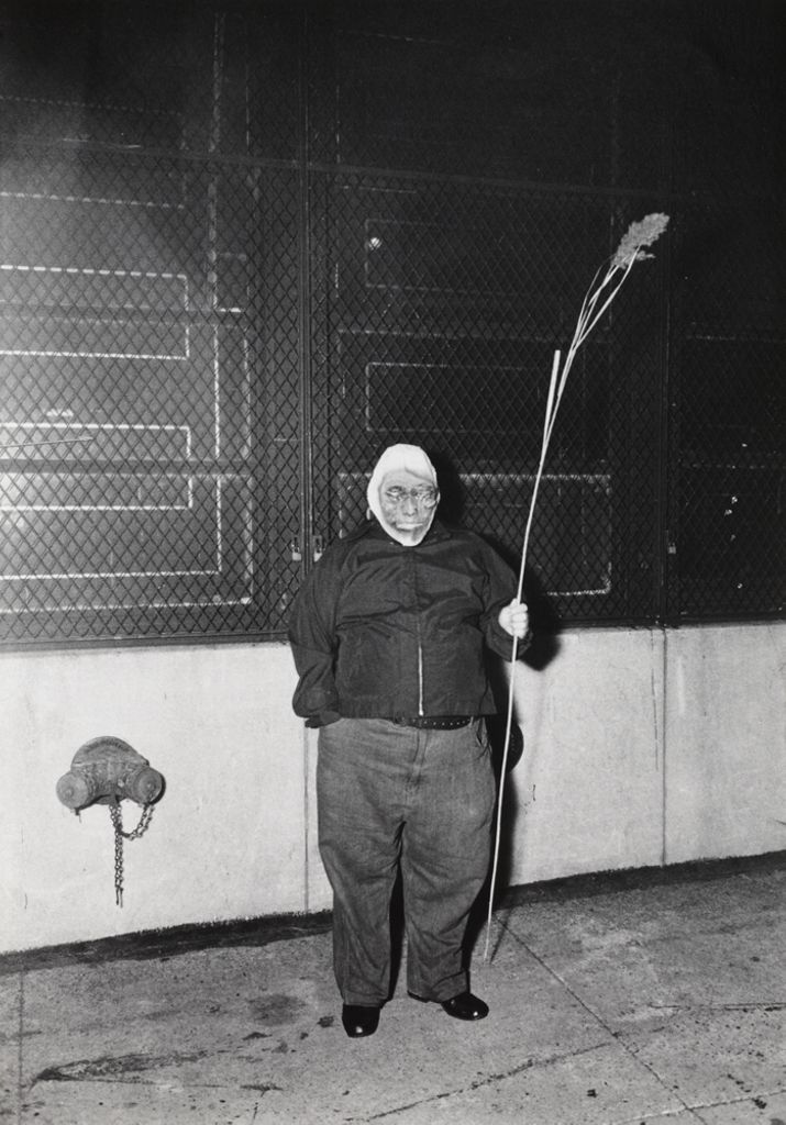 person in a Halloween mask and baggy clothes holding a thin stick