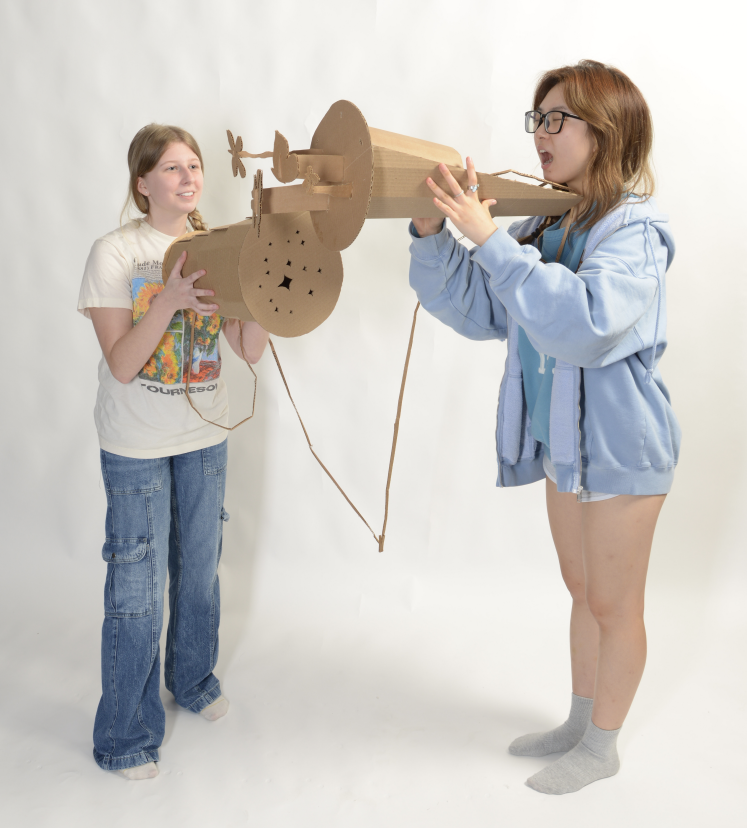 two women holding cardboard cylinder shaped microphones