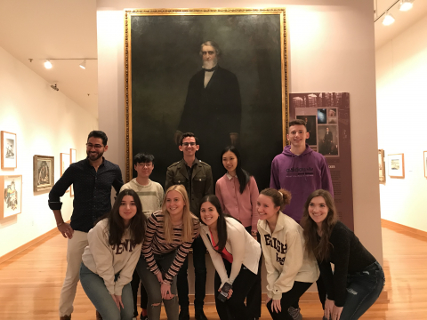 college students standing in front of a large painting of a man