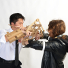 Two figures fighting with cardboard knives that are attached to their forearms 