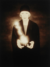 A woman in a black hat and jacket holding smoke